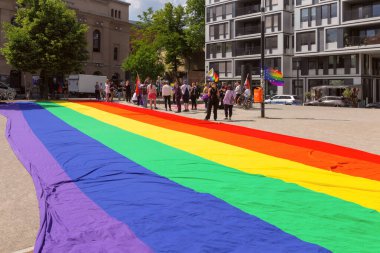 Berlin, Almanya - 23 Mayıs 2024: Bertolt Brecht Meydanı 'nda parlak gökkuşağı bayrakları ve sembollerle LGBT topluluk toplantısı.