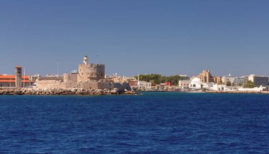 Mandraka limanı, Rodos, Yunanistan 'da mavi denizin arka planında güneşli eski bir deniz feneri manzarası.