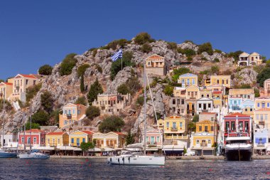 Güneşli bir günde, Suriye köyünde renkli geleneksel evler ve balıkçı tekneleri, Yunanistan ve Dodecanese manzarası.