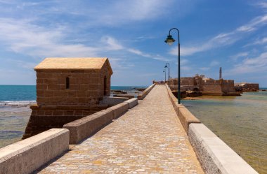 San Sebastian Kalesi 'nin manzarası ve ona ışık tutan taş köprü parlak güneşli bir günde, Cadiz, Endülüs, İspanya