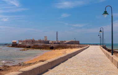 San Sebastian Kalesi 'nin manzarası ve ona ışık tutan taş köprü parlak güneşli bir günde, Cadiz, Endülüs, İspanya