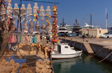 Mandraki eski limanının güneşli bir günde deniz kabukları ve hediyelik eşyalarla dolu bir balıkçı teknesi manzarası, Rodos, Yunanistan
