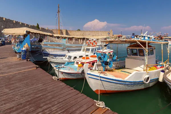 Mandraki eski limanının güneşli bir günde deniz kabukları ve hediyelik eşyalarla dolu bir balıkçı teknesi manzarası, Rodos, Yunanistan