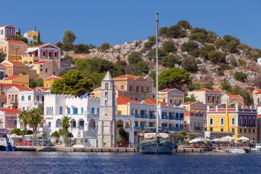 Güneşli bir günde, Suriye köyünde renkli geleneksel evler ve balıkçı tekneleri, Yunanistan ve Dodecanese manzarası.
