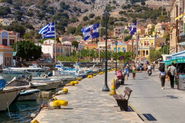 Symi, Yunanistan - 16 Eylül 2023: Güneşli bir yaz gününde kent seti üzerinde turistler