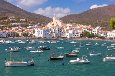 Kadavra Koyu manzarası. Suda küçük tekneler, beyazlatılmış evler, Santa Maria Kilisesi ve arka planda dağlar, İspanya, Katalonya.