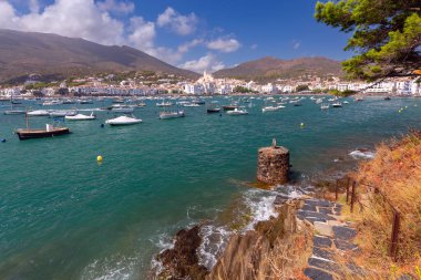 Kadavra Koyu manzarası. Suda küçük tekneler, beyazlatılmış evler, Santa Maria Kilisesi ve arka planda dağlar, İspanya, Katalonya.