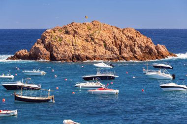 Tossa de Mar, İspanya ve Katalonya 'nın kıyı sularında kayalık adanın yakınında yüzen mavi körfezdeki teknelerin resimli görüntüsü.