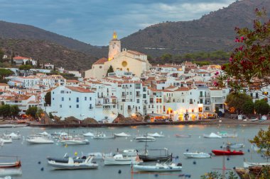 Kadavra manzarası, Santa Maria kilisesi ve gezinti alanı boyunca uzanan geleneksel beyaz Akdeniz binaları, gün batımında körfezde kayıklar, İspanya, Katalonya