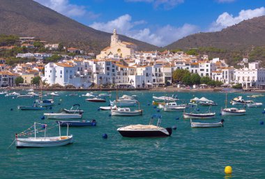 Kadavra Koyu manzarası. Suda küçük tekneler, beyazlatılmış evler, Santa Maria Kilisesi ve arka planda dağlar, İspanya, Katalonya.