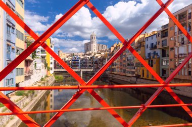 Girona Katedrali, Onyar Nehri üzerindeki Eyfel Köprüsü 'nün kırmızı demir çerçevesinden ve Katalonya, İspanya' daki renkli binalardan görülür.