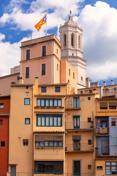 Girona Katedrali 'nin kulesi, İspanya' nın Girona kentindeki güneşli bir günde eski kasabadaki renkli konut binalarının üzerinde yükselir..