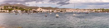 Panoramic view of the coast of Cadaques, Spain, with Santa Maria church, white buildings and boats in the harbor clipart