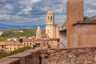 Katedralin çan kulesi Girona 'da kiremitli çatıları olan geleneksel taş binaların üzerinde parlak mavi gökyüzüne, İspanya' ya, Katalonya 'ya karşı yükselir.