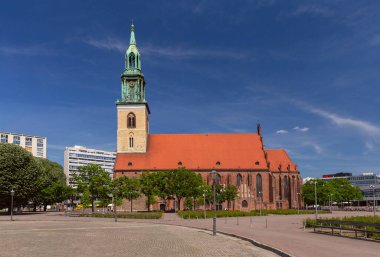 Güneşli bir günde Berlin 'deki St. Marys Kilisesi saat kulesi ve çevresindeki yeşilliklerle, Almanya