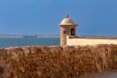 Cadiz 'deki tarihi kıyı gözlem kulesi, okyanusa bakıyor, önünde taş duvar var, İspanya