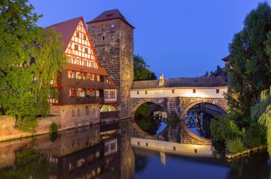 Night view of the historic Weinstadel building and Max Bridge reflecting in the Pegnitz River in Nuremberg, Germany clipart