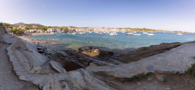 Scenic coastal path crossing the Pont de Sortel bridge on the rocky coast in Cadaques leading to the pine-lined island of SArenella, Spain clipart