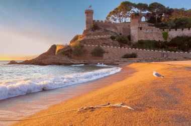 İspanya 'nın Tossa de Mar kentindeki kumlu kumlu sahilin sabah manzarası. Mavi gökyüzüne, İspanya' ya, Katalonya 'ya çarpan dalgalar.