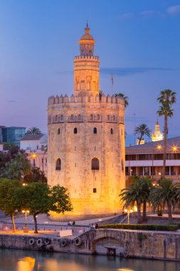 Torre del Oro 'nun akşam manzarası Sevilla, İspanya' daki Guadalquivir nehri boyunca ışıklarla aydınlandı.