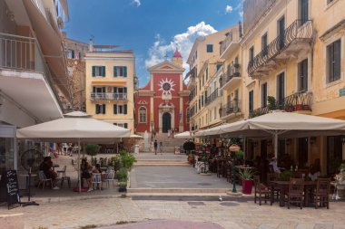 Yunanistan, Kerkyra - 20 Eylül 2021: Korfu 'da Aziz James ve Aziz Christopher Katolik Katedrali cephesi, kafeler ve ön planda insanlar