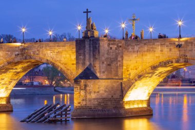 Prag Çek Cumhuriyeti 'ndeki Charles Köprüsü' nün yakın görüntüsü alacakaranlıkta Vltava Nehri üzerinde aydınlık heykeller ve kemerler ile