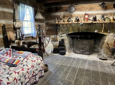 1800 'lerin evinde şömine, dönen tekerlek ve yatak. Mitchell, Indiana yakınlarındaki Spring Mill Parkı' ndaki yenilenmiş ve yenilenmiş Pioneer Village 'da..