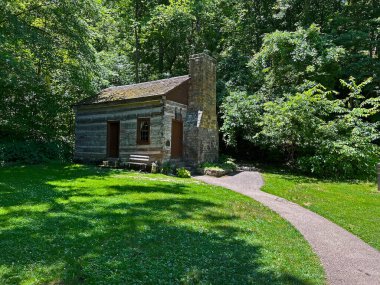 İndiana, Mitchell yakınlarındaki Spring Mill State Park 'taki 1800 Pioneer Village' da yeniden inşa edilmiş ve restore edilmiş çömlek ve ahşap atölyesinin önünde yeşil çimen fotokopi alanı ile.