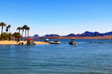Havasu Gölü, Arizona, ABD 'de Bridgewater Kanalı' ndaki bir sahilde mavi gökyüzü fotokopi alanı ve Kaliforniya dağları olan Havasu Gölü 'nde tekneler..