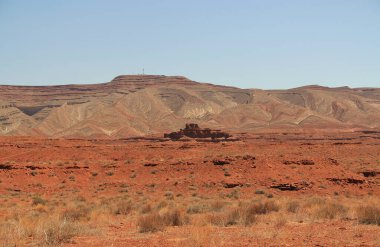 Meksika Şapkası yakınlarındaki Anıt Vadisi 'nde uzanan dağlar, Güney Utah' ta, ABD 'de, San Juan' da, Navajo Milletleri sınırlarında, mavi gökyüzü ve kayalık kopya uzayı ile kırmızı kaya oluşumu.. 