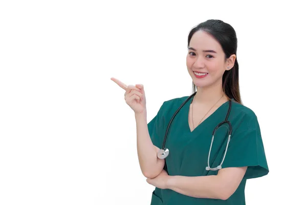 白い背景の上を指しながら 緑の制服を着たプロのアジア人女性医師が立って笑顔 — ストック写真