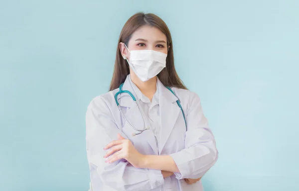 腕を組んで立っているプロの若いアジアの女性医師は マスクと聴診器を身に着けて白いローブを身に着けて渡った コロナウイルスの保護は病気や健康の概念を防ぐ — ストック写真