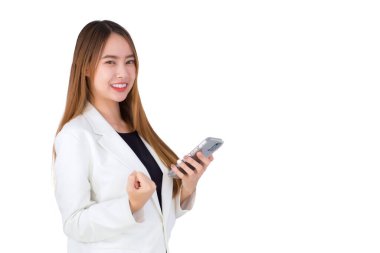 Beyaz takım elbiseli güzel Asyalı iş kadını kameraya bakarken mutlu bir şekilde gülümsüyor ve beyaz arka planda tek başına akıllı telefon tutuyor...