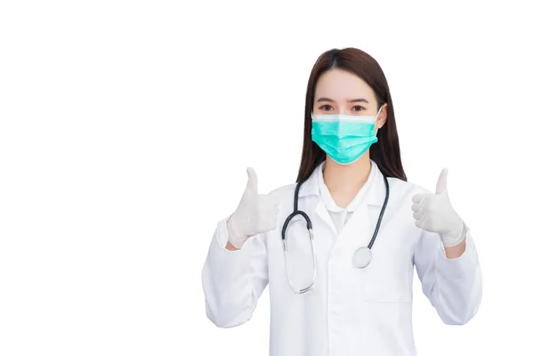 医療用のコートとフェイスマスクを身に着けているプロの若いアジアの女性医師は 白い背景に隔離されながら 病院での健康保護の概念に良い兆候としてThumpを示しています — ストック写真