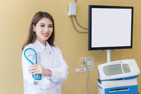 プロの若いアジアの女性医師は 白いローブと腕で立っているスタチオスコープを着用し 病院の検査室で幸せで笑顔を交差させました — ストック写真