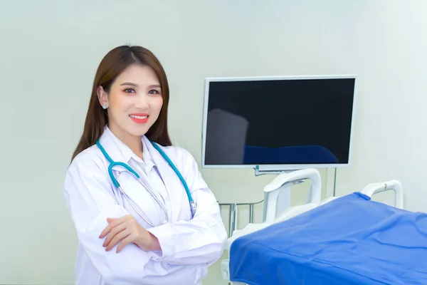 プロの若いアジアの女性医師は 腕で立っている白いローブを着ています ホワイトローブとステスコープを着て 病院の検査室で幸せで笑顔で — ストック写真