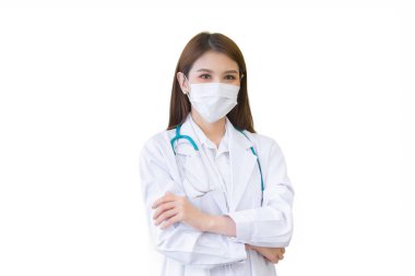 Genç profesyonel Asyalı kadın doktor, sağlık kirliliği PM2.5 ve virüs koruma kavramlarında beyaz arka planda izole edilirken hastanede çalışırken kollarını kavuştururken tıbbi ceket ve yüz maskesi takıyor..