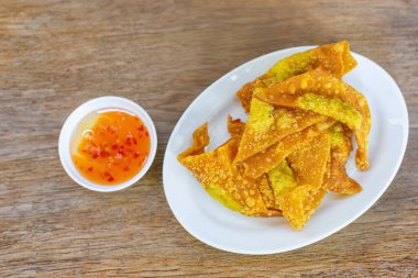 Lezzetli Tayland usulü çıtır ev yapımı domuz etli börek, beyaz seramik tabakta, seramik bardakta sos ahşap masada Tayland mezeleri..
