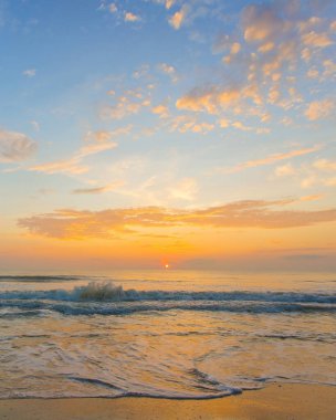 Gün batımının 16.5 dikey görüntüsü yumuşak deniz dalgaları ve canlı mavi-turuncu gökyüzü, akşam manzarası için ideal..