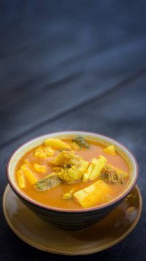 Dikey 9: 16 'lık Güney Tayland baharatlı ekşi Hint cevizi filizli ve deniz balıklı köri otantik geleneksel yemek arka planı için kırsal ahşap masada servis edilir..