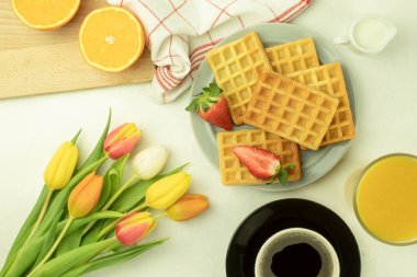 Tabakta taze pişmiş ev yapımı waffle 'lar. Çilekli ev yapımı waffle. Laleler ve kahve waffle 'ları. Yan görünüm