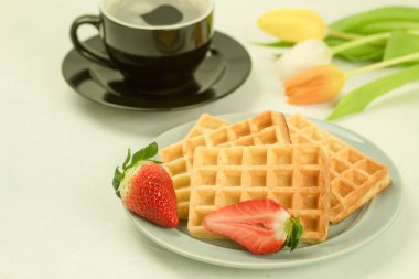 Tabakta taze pişmiş ev yapımı waffle 'lar. Çilekli ev yapımı waffle. Laleler ve kahve waffle 'ları. Yan görünüm