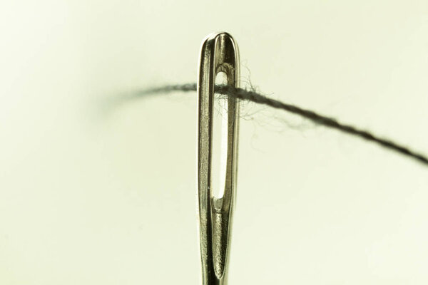 The eye of a needle with a thread close-up. Sewing needle with penetrating thread. Tool for sewing, embroidery