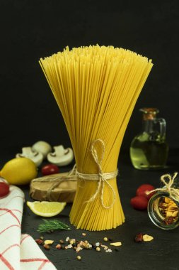 Kuru spagetti, iple bağlanmış bir demet spagetti. Makarna, kaliteli fotoğraf. Dikey fotoğraf. Boşluğu kopyala