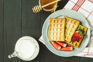 Meyveli taze Belçika waffleları, üst manzara. Lezzetli bir kahvaltı. Çilekli ev yapımı waffle tabakta toz şeker, ahşap bir arka planda. Metin için boşluk