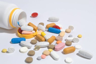 Masada bir sürü hap var, yakın plan. Tabletler farklı şekiller ve renkler masaya saçılmış. Haplar şişeden döküldü.