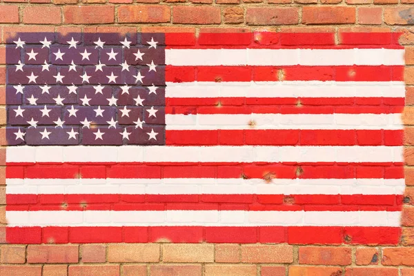 The American flag is painted on a brick wall. Flag on an old stone wall