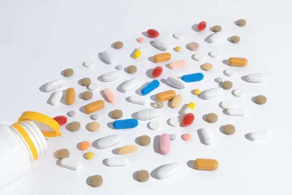 テーブルの上に多くの薬を クローズアップ テーブルの上にはさまざまな形や色の錠剤が散乱しています 薬が瓶からこぼれた — ストック写真