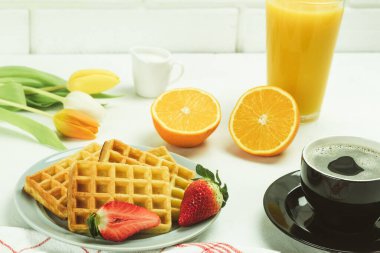 Kahvaltıda Belçika waffle 'ı ve taze meyve. Taze portakal suyu, Viyana waffle 'ı ve taze çiçeklerle birlikte kahve.