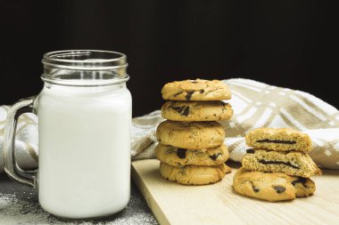 Fırında pişmiş kurabiye ve tepside çikolata. Çikolata parçalı kurabiyeler istiflenmiş. Metin için boşluk